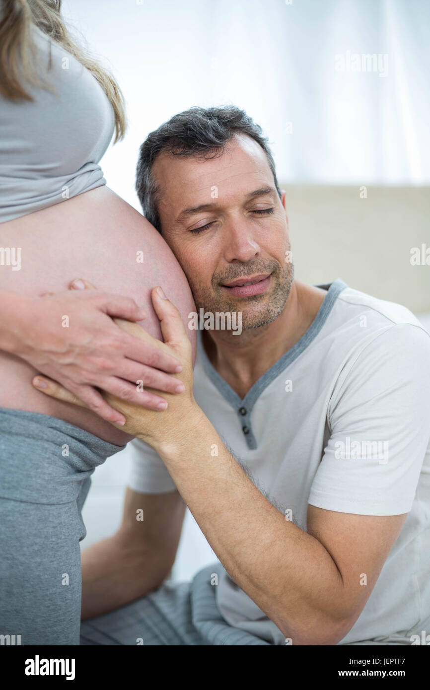 Man listening to pregnant womans stomach Stock Photo