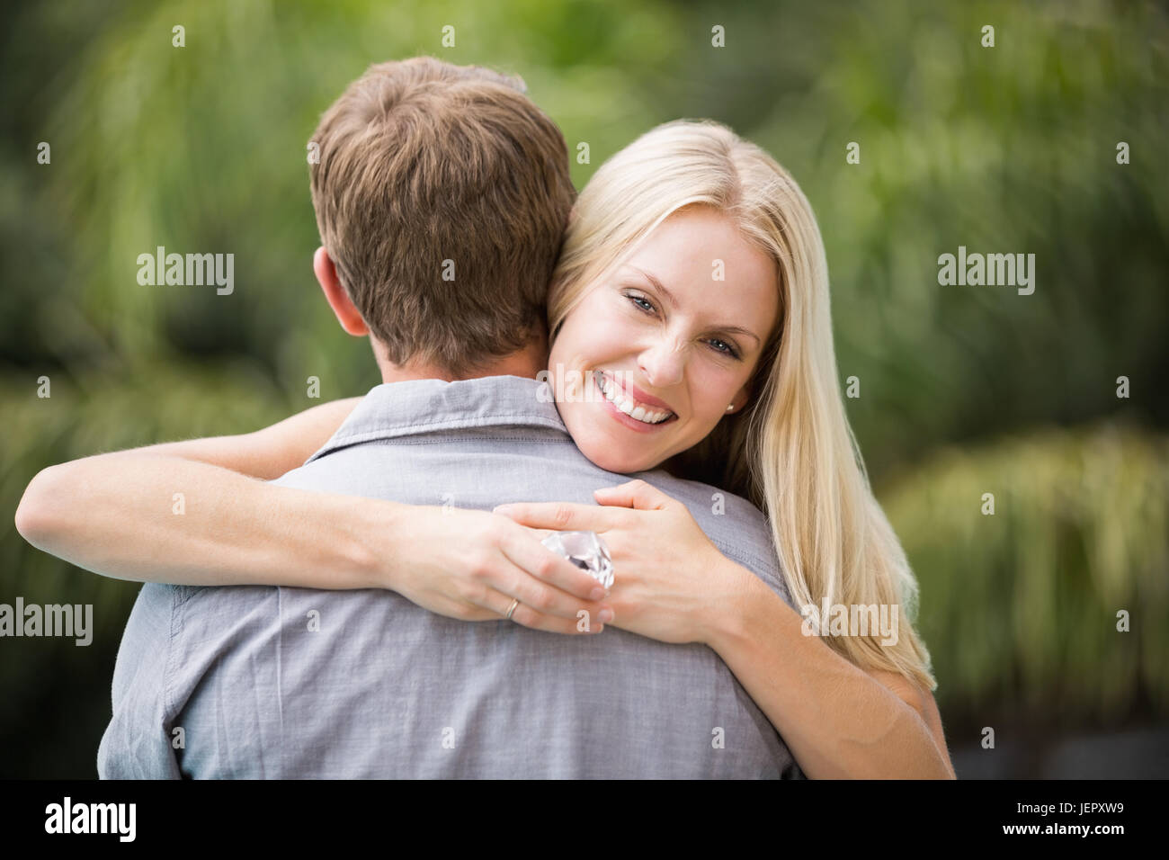 Smiling young woman hugging man Stock Photo - Alamy