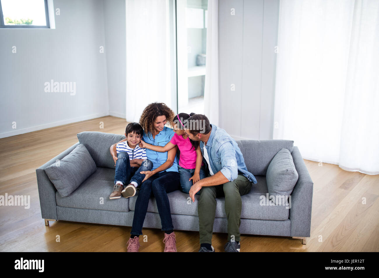 Happy family sitting together on sofa Stock Photo - Alamy