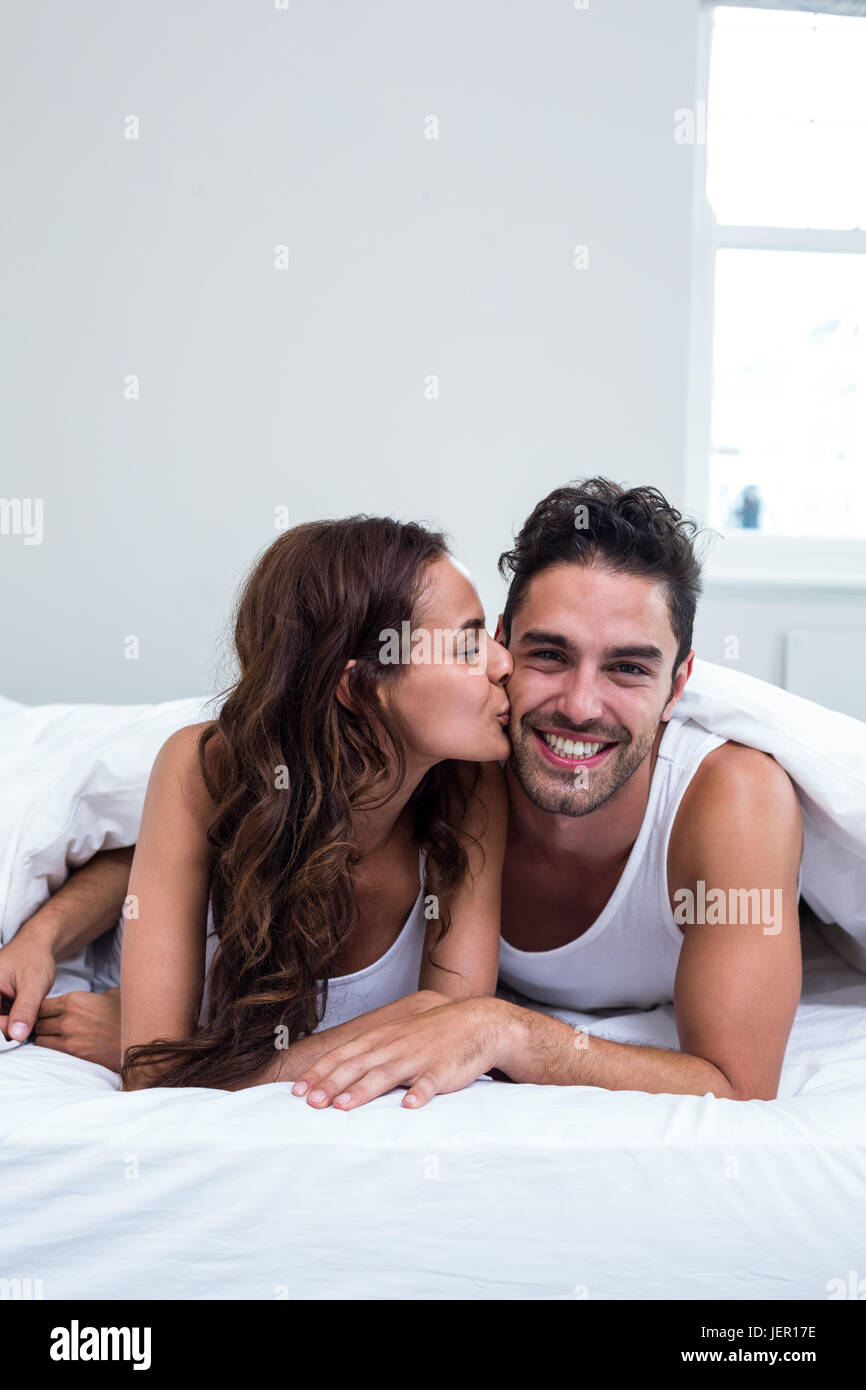 Woman kissing man while lying under blanket Stock Photo Alamy