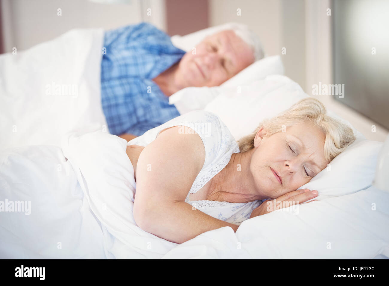 Senior woman sleeping besides husband on bed Stock Photo Alamy