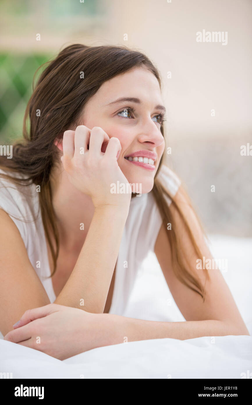 Thoughtful smiling woman lying on bed Stock Photo