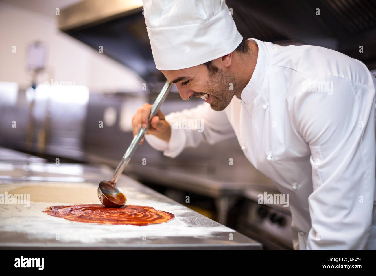 Pizza chef put sauce on base Stock Photo Alamy