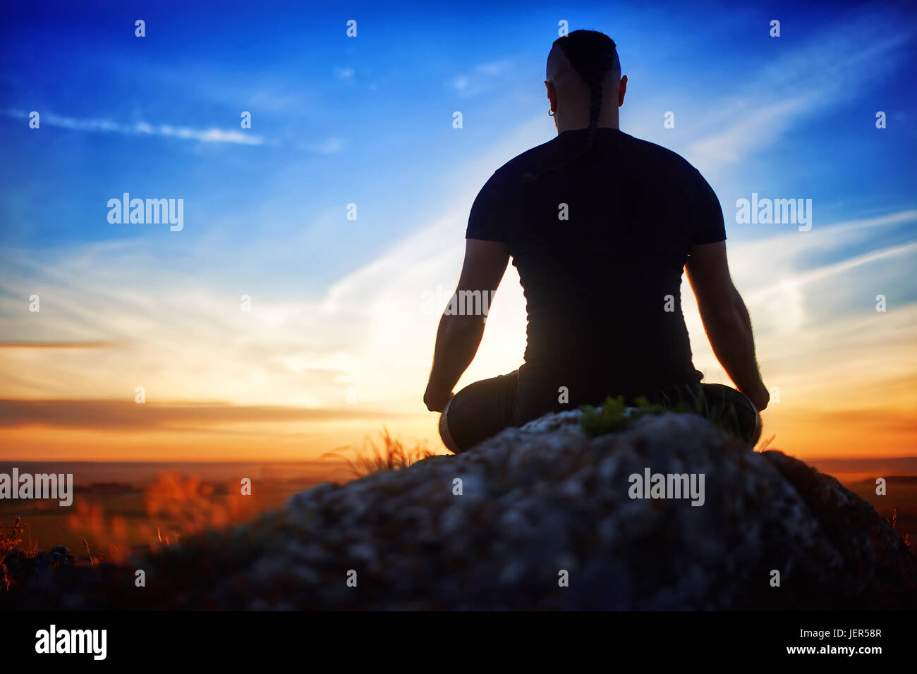 Rear view of the fit young man meditating yoga in lotus pose on the ...