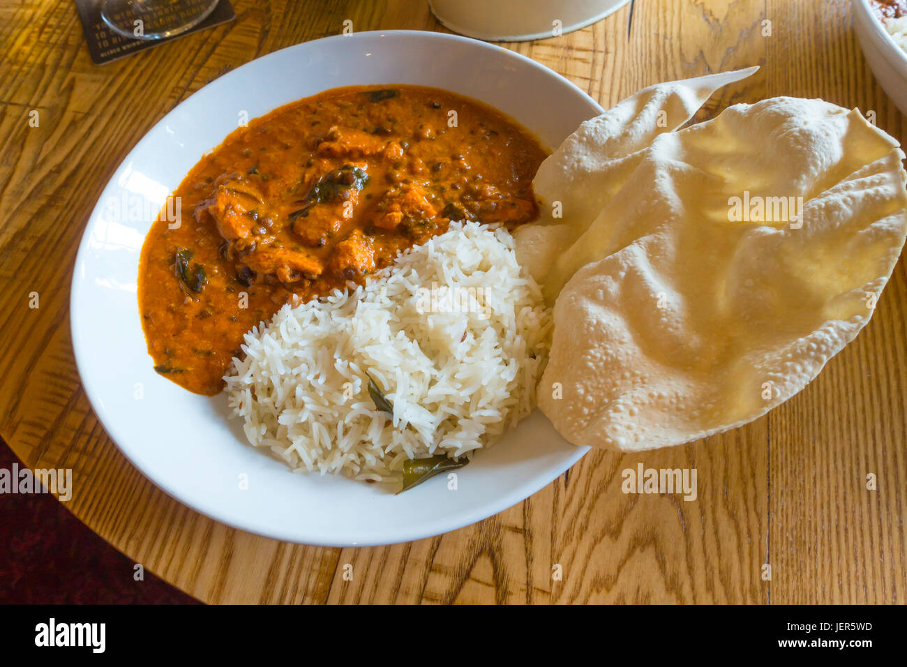 Pub meal Chicken Tikka Makhani Tandoori with chicken pieces lentil cashew nut and spinach sauce with cumin infused tadka rice and a crisp poppadom Stock Photo