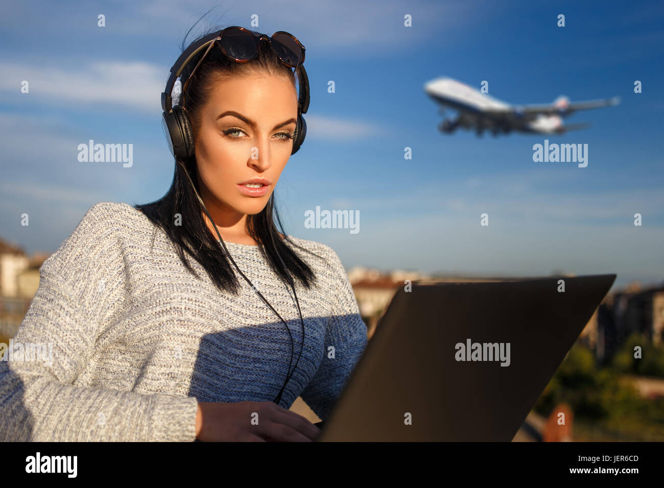 Young woman purchasing air ticket by laptop outdoor Stock Photo