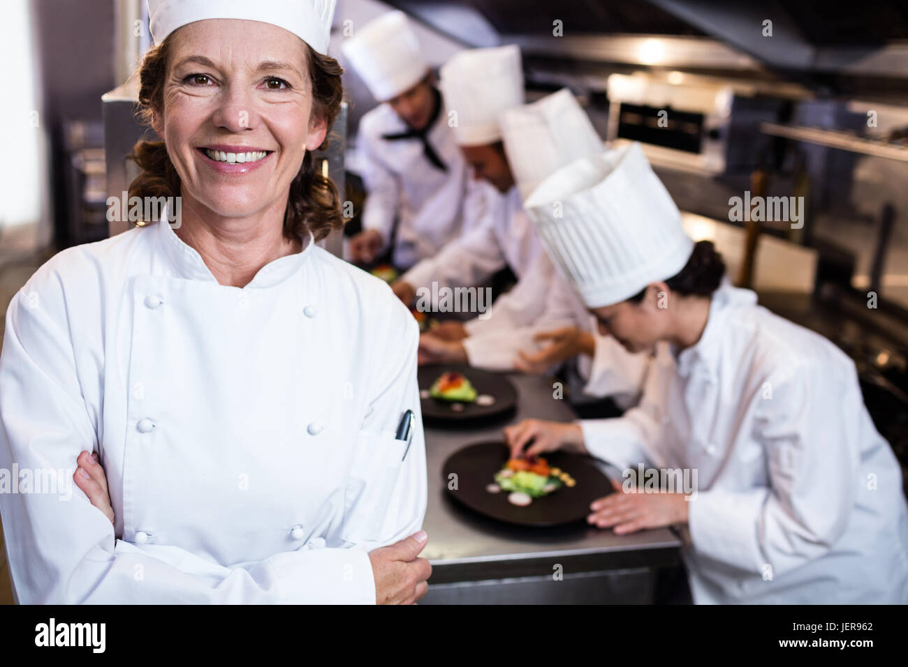 Head chef smiling in busy kitchen Stock Photo Alamy