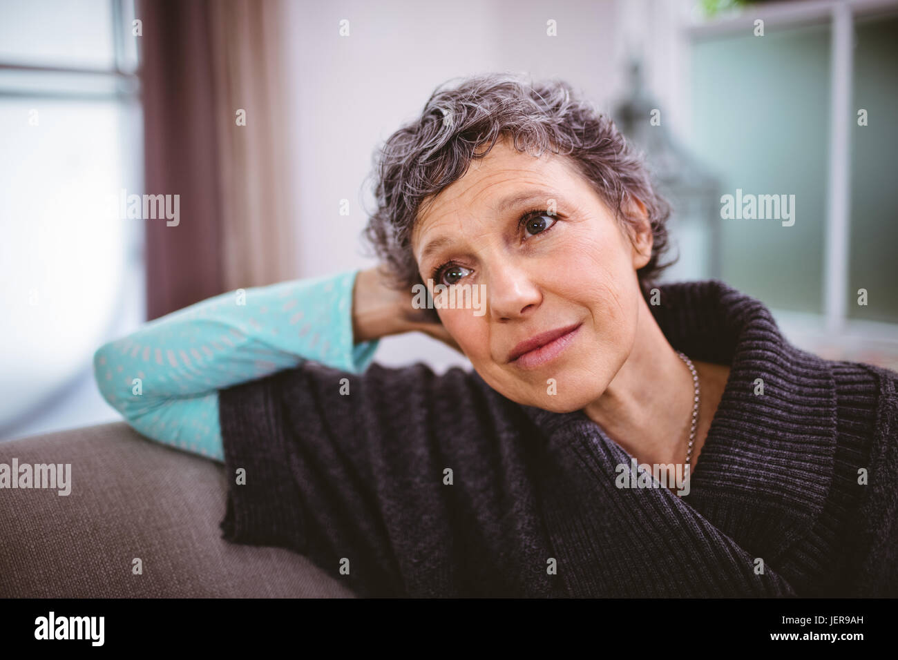 Mature woman sitting on sofa hi-res stock photography and images - Alamy