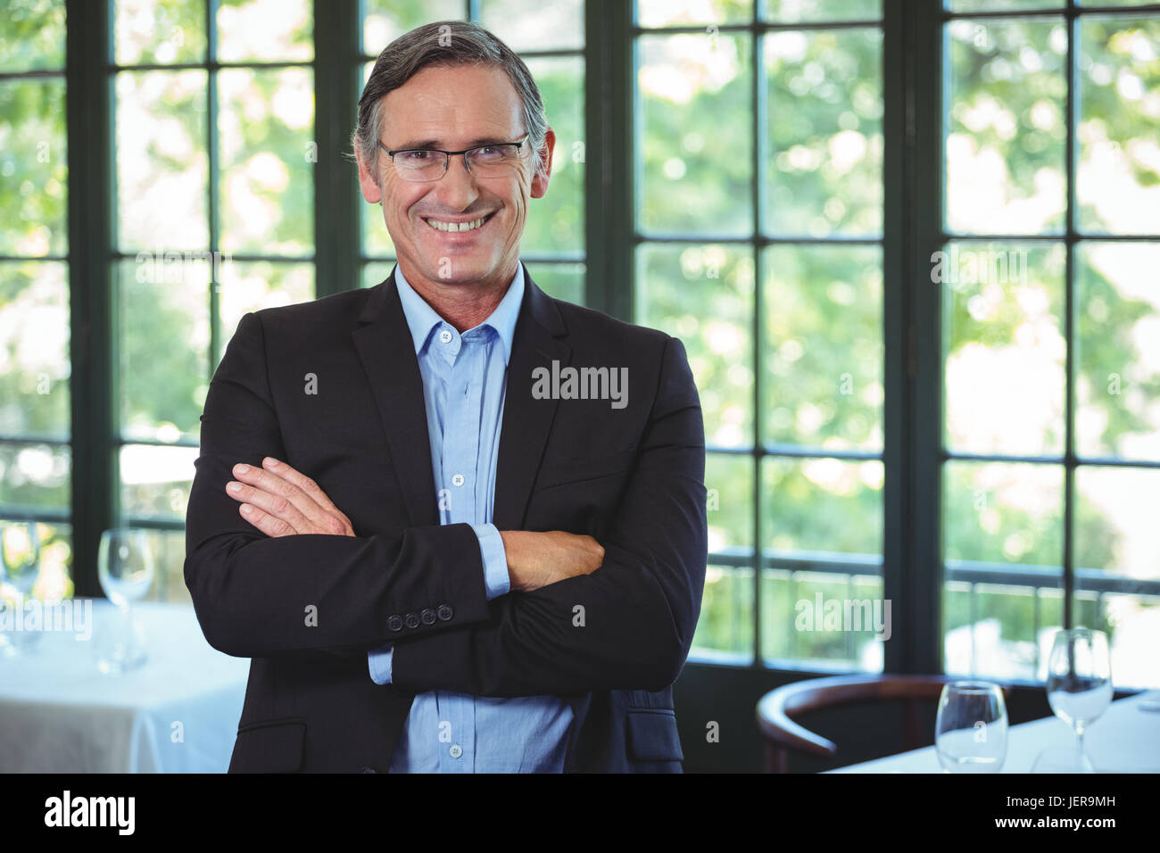 Smiling businessman posing with crossed arms Stock Photo - Alamy