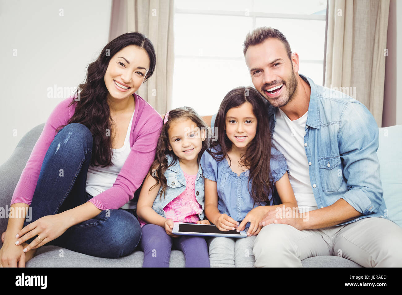 Family with tablet computer sitting on sofa Stock Photo