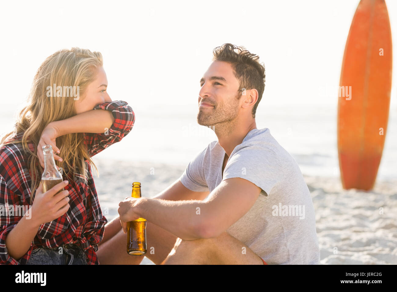 Couple sitting on sand at the beach Stock Photo - Alamy