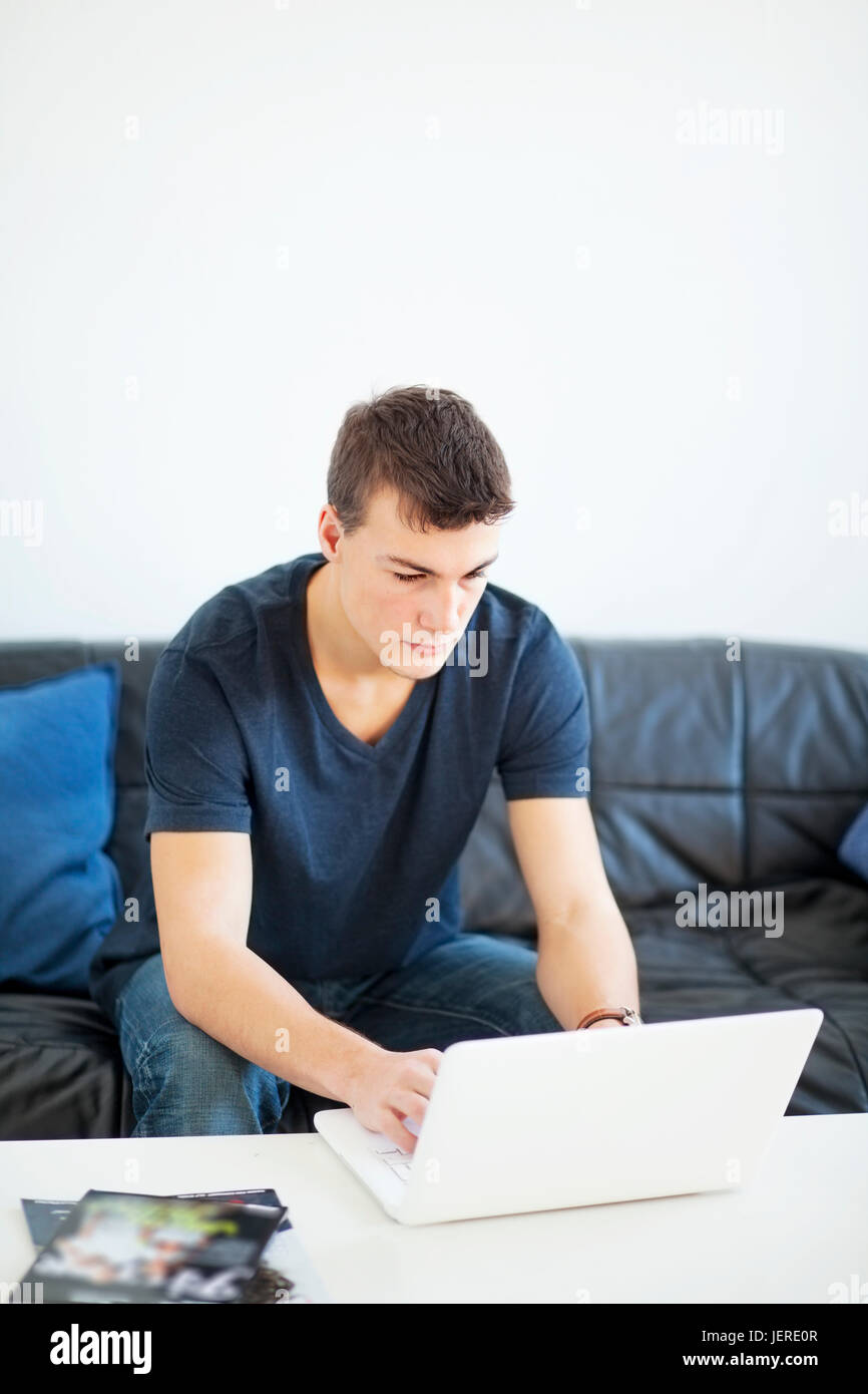 Teenage boy on sofa using laptop Stock Photo - Alamy