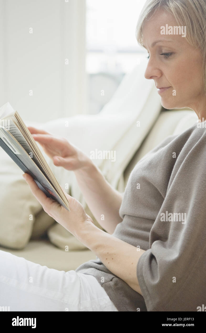 Woman reading book on sofa Stock Photo