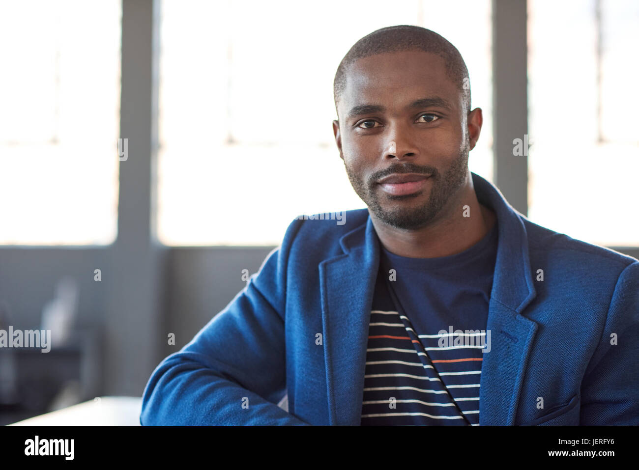 Portrait of a confident young African businessman in a blazer smiling ...