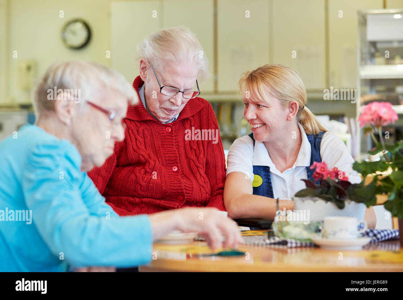 Nurse in care home talking with senior patients Stock Photo