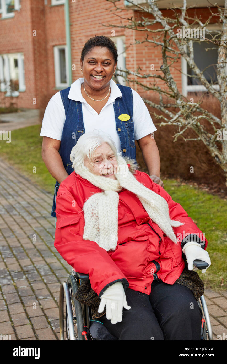 Nurse on walk with senior woman on wheelchair Stock Photo