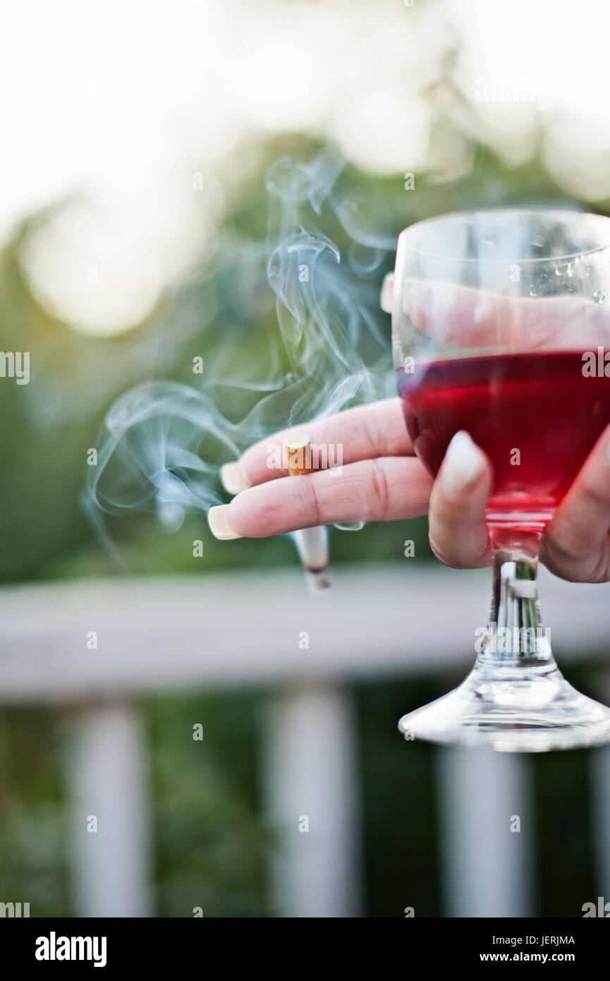 Womans hand holding cigarette and glass of wine Stock Photo - Alamy
