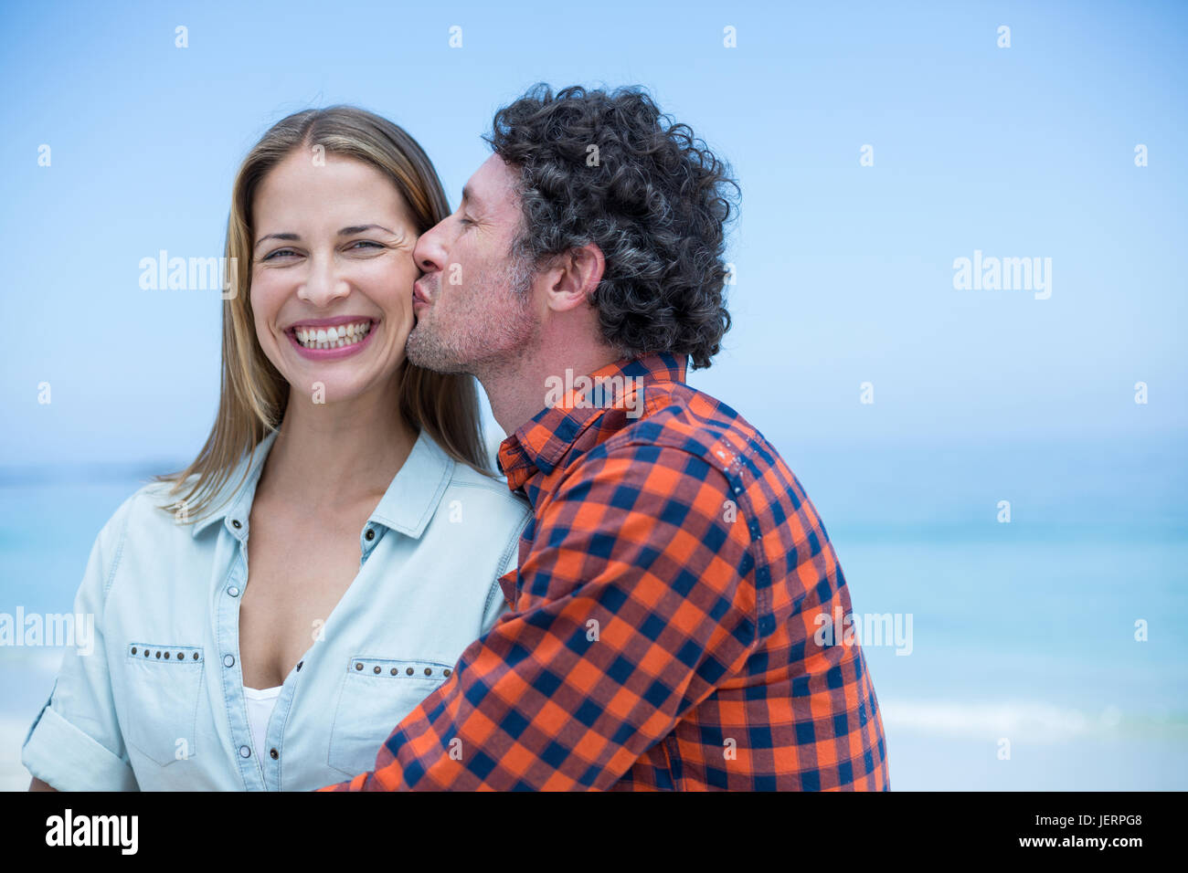 Man kissing happy woman at sea shore Stock Photo - Alamy
