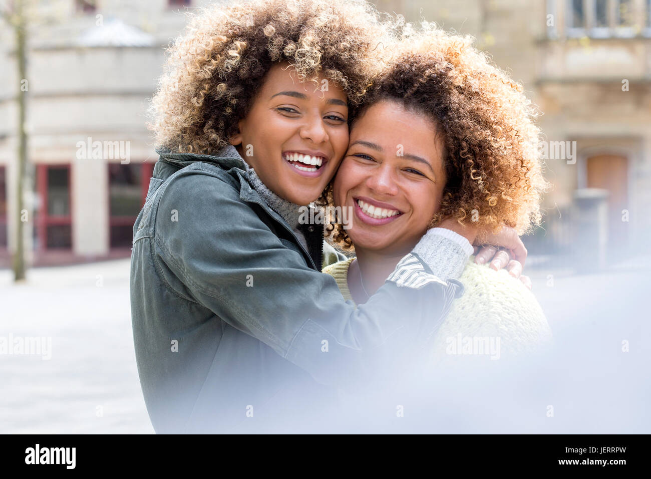 Two friends hugging and smiling for the camera in the city Stock Photo ...