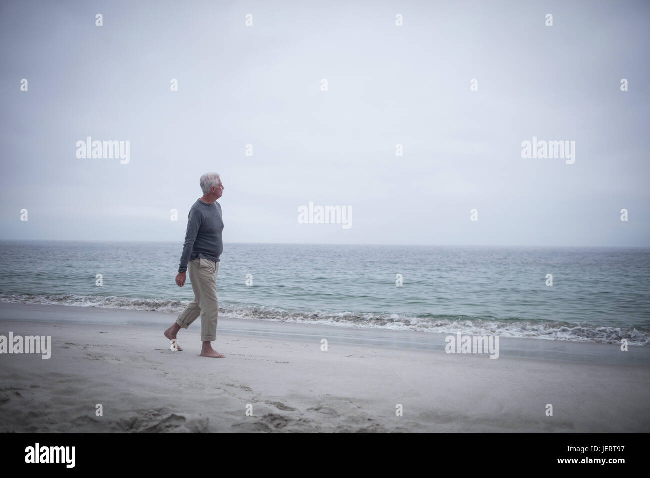 Thoughtful Retired Man Walking On The Beach Stock Photo - Alamy