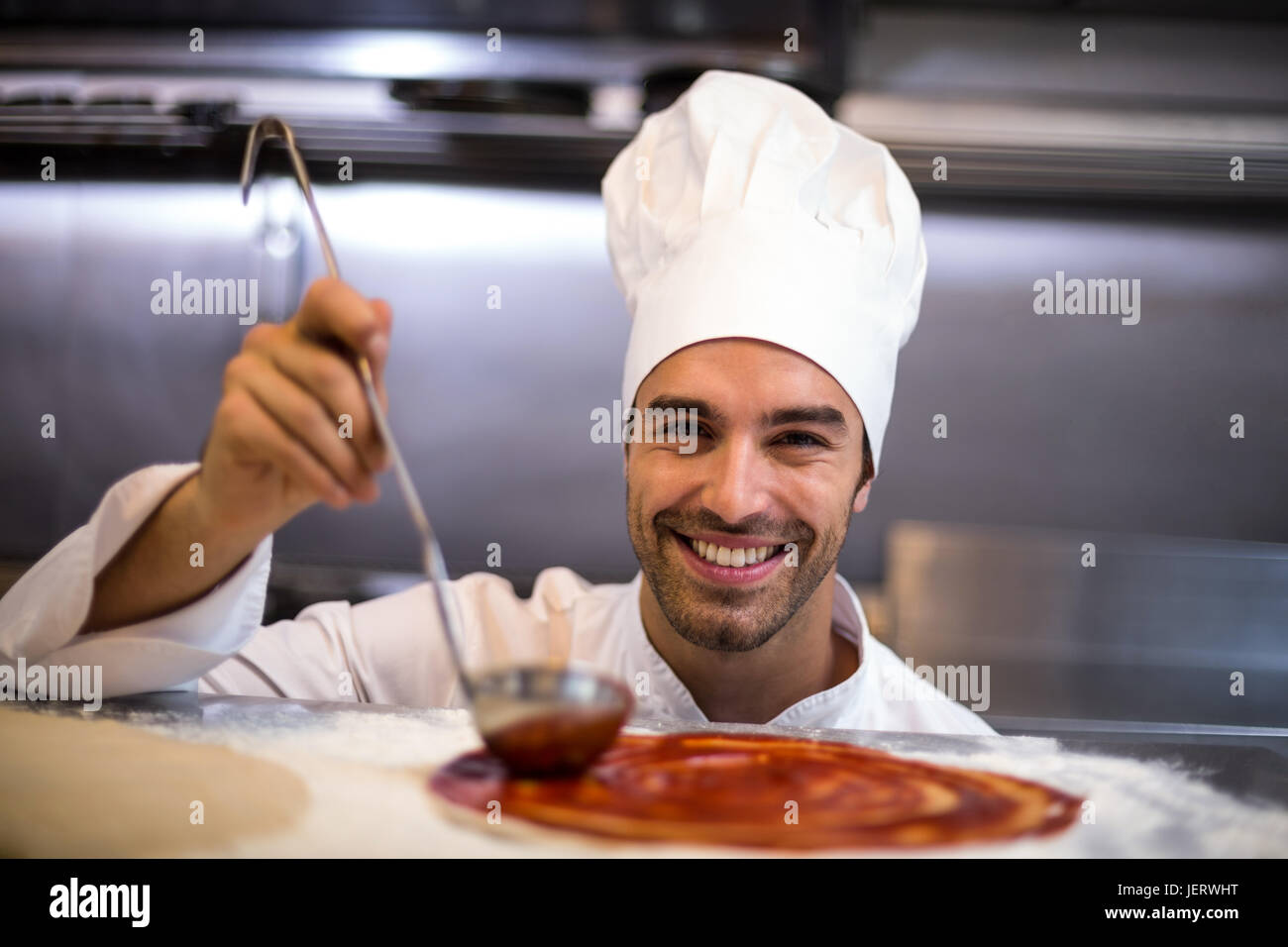 Pizza chef put sauce on base Stock Photo Alamy