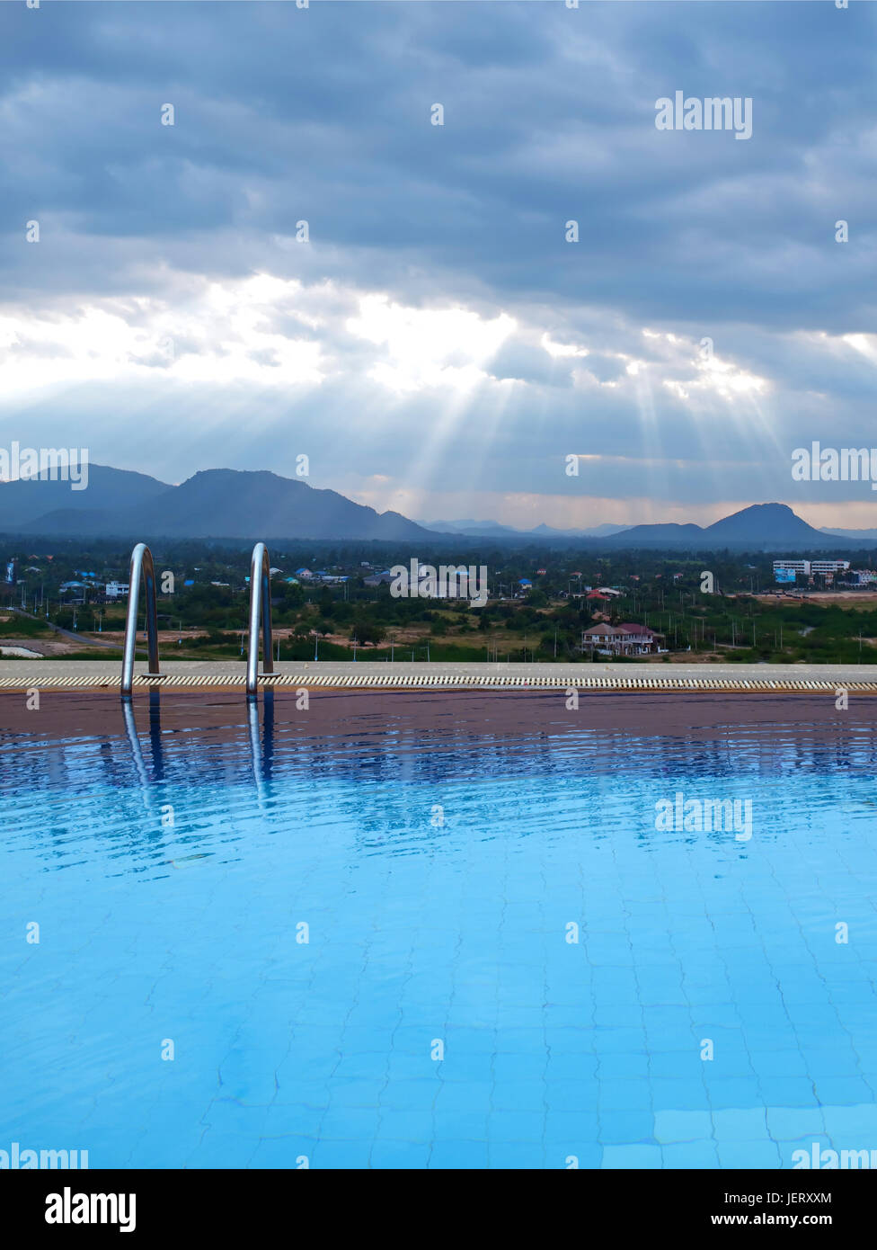 Outdoor swimming pool with sunbeam over mountains Stock Photo