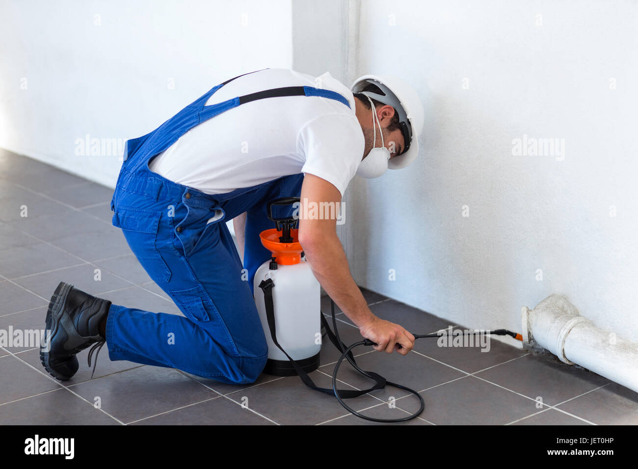 Manual worker spraying insecticide on pipe Stock Photo