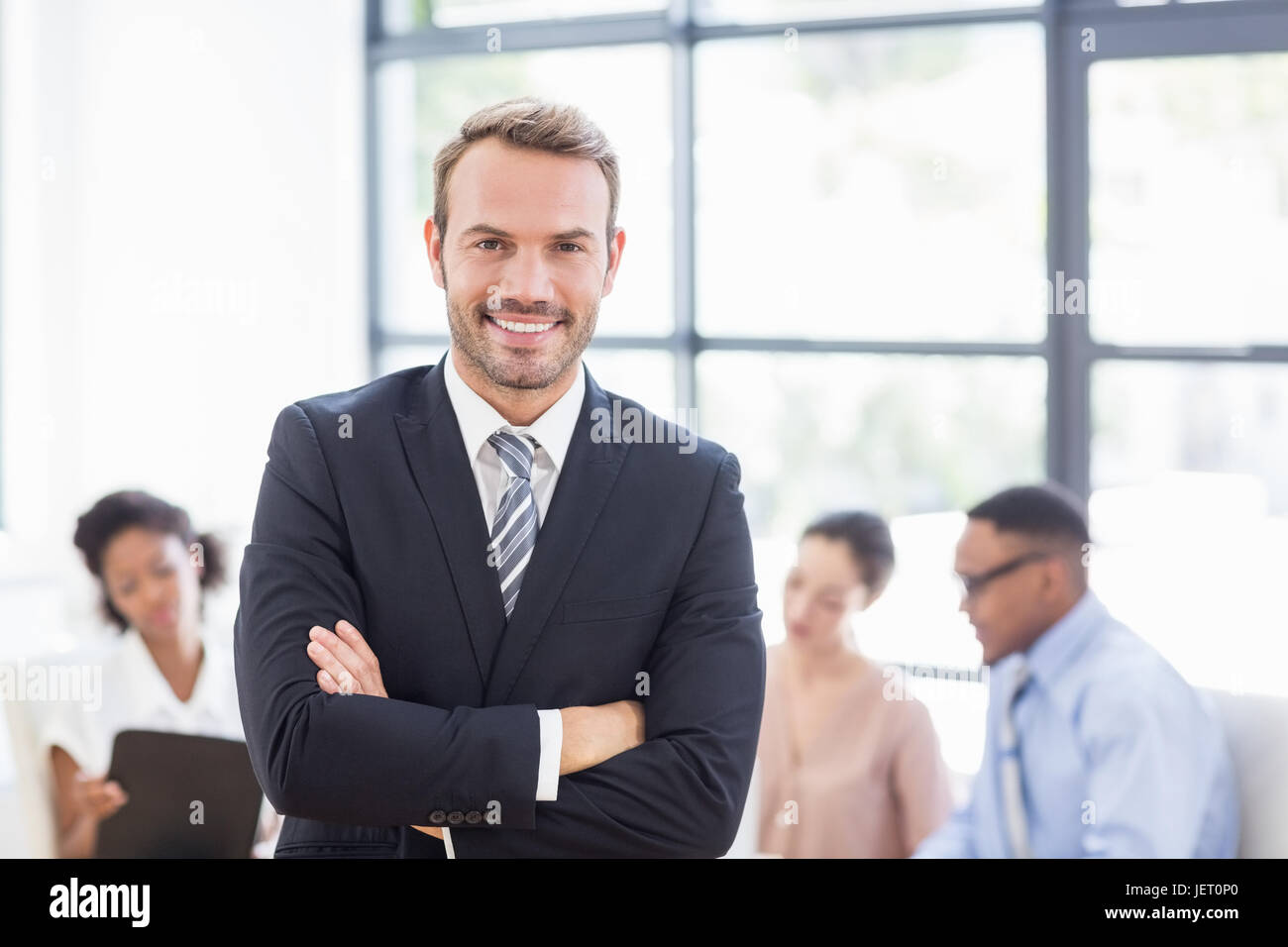 Happy businessman standing with arms crossed Stock Photo - Alamy