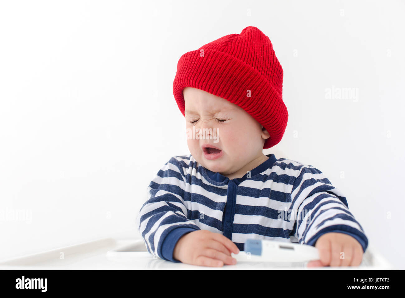 The baby sneezes with thermometer on a white background Stock Photo