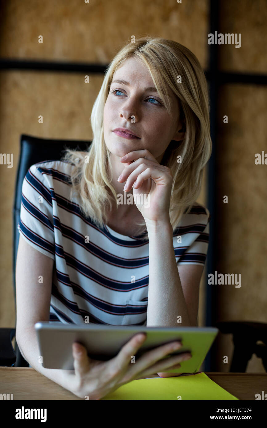 Thoughtful young woman holding digital tablet Stock Photo - Alamy