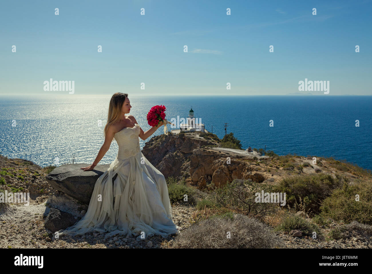 Beautiful woman in white dress on a stone near the sea Stock Photo - Alamy