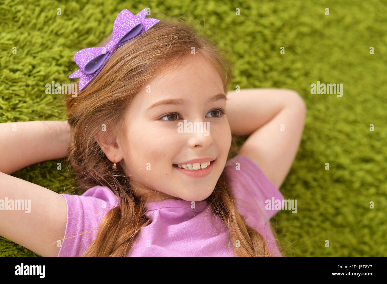 Portrait of a smiling little girl lying on carpet Stock Photo - Alamy