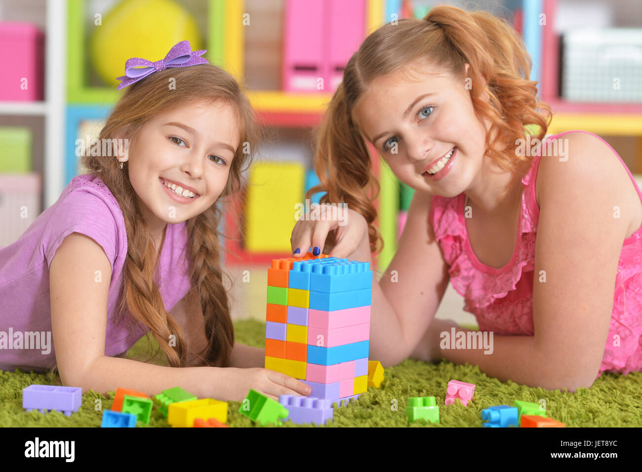 Cute girls playing with colorful plastic blocks in room Stock Photo - Alamy