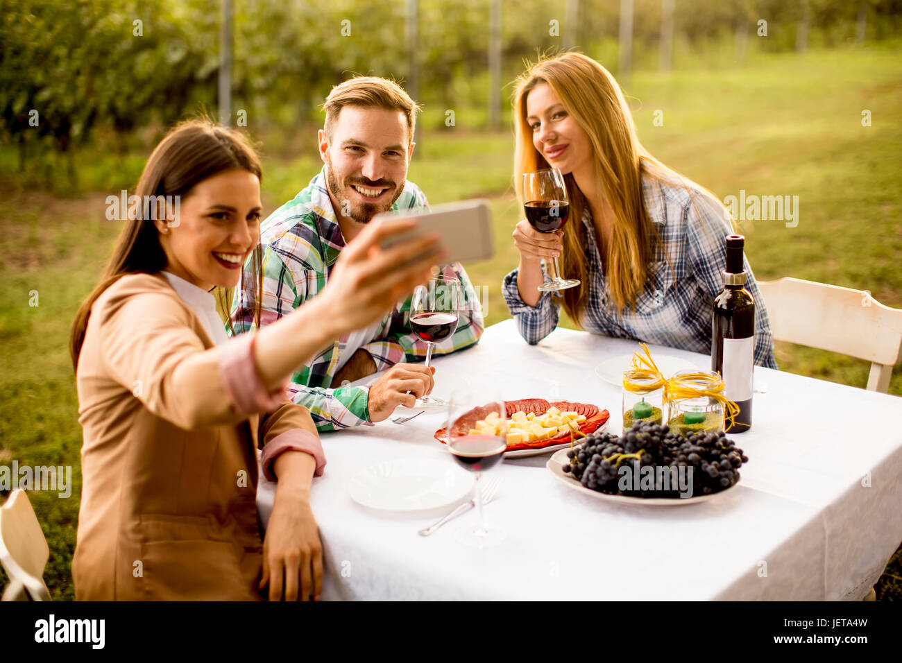 Group of young people sitting by the table and drinking red wine in the ...