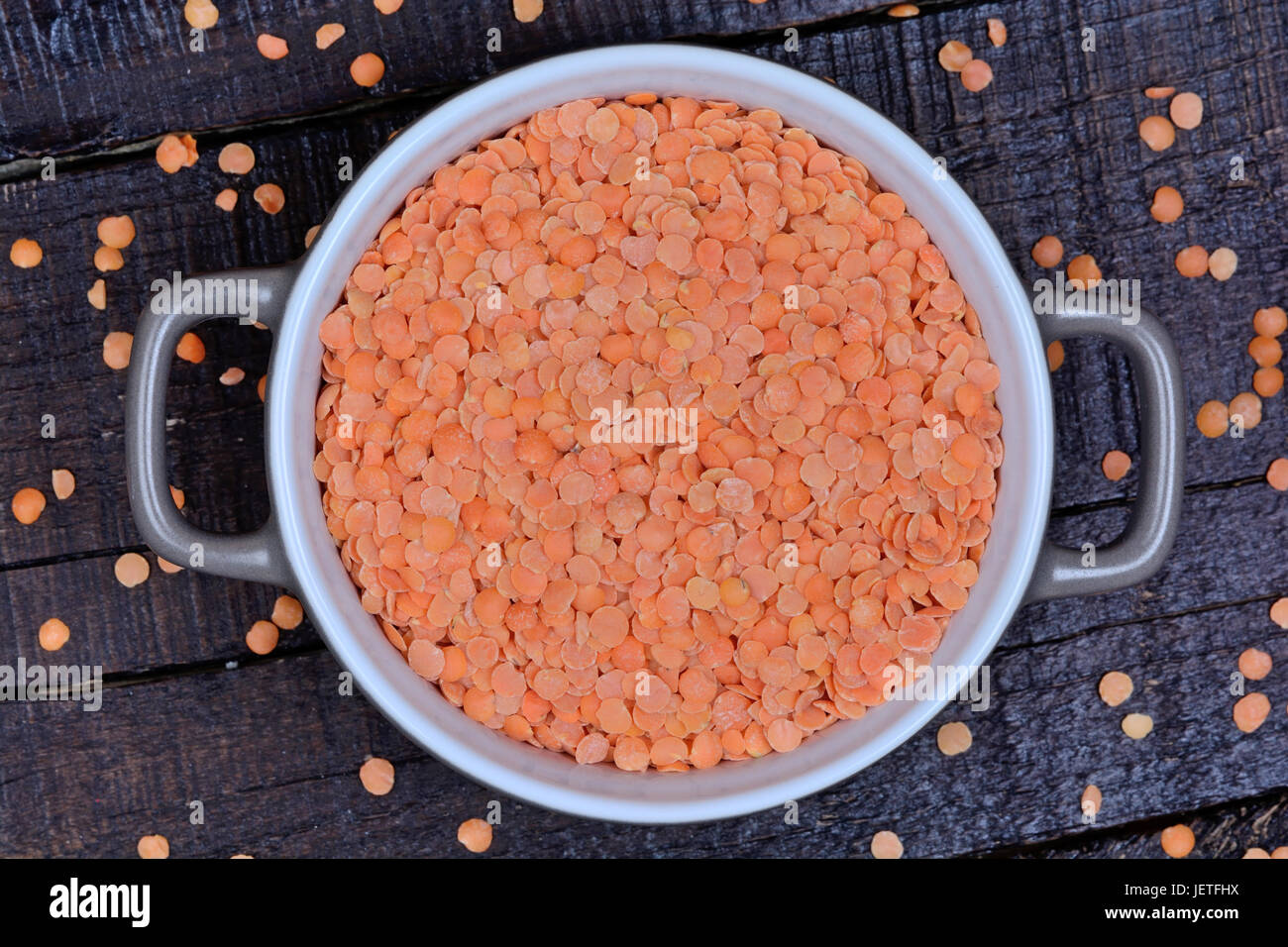 Red lentils in a ceramic pot on wooden background Stock Photo
