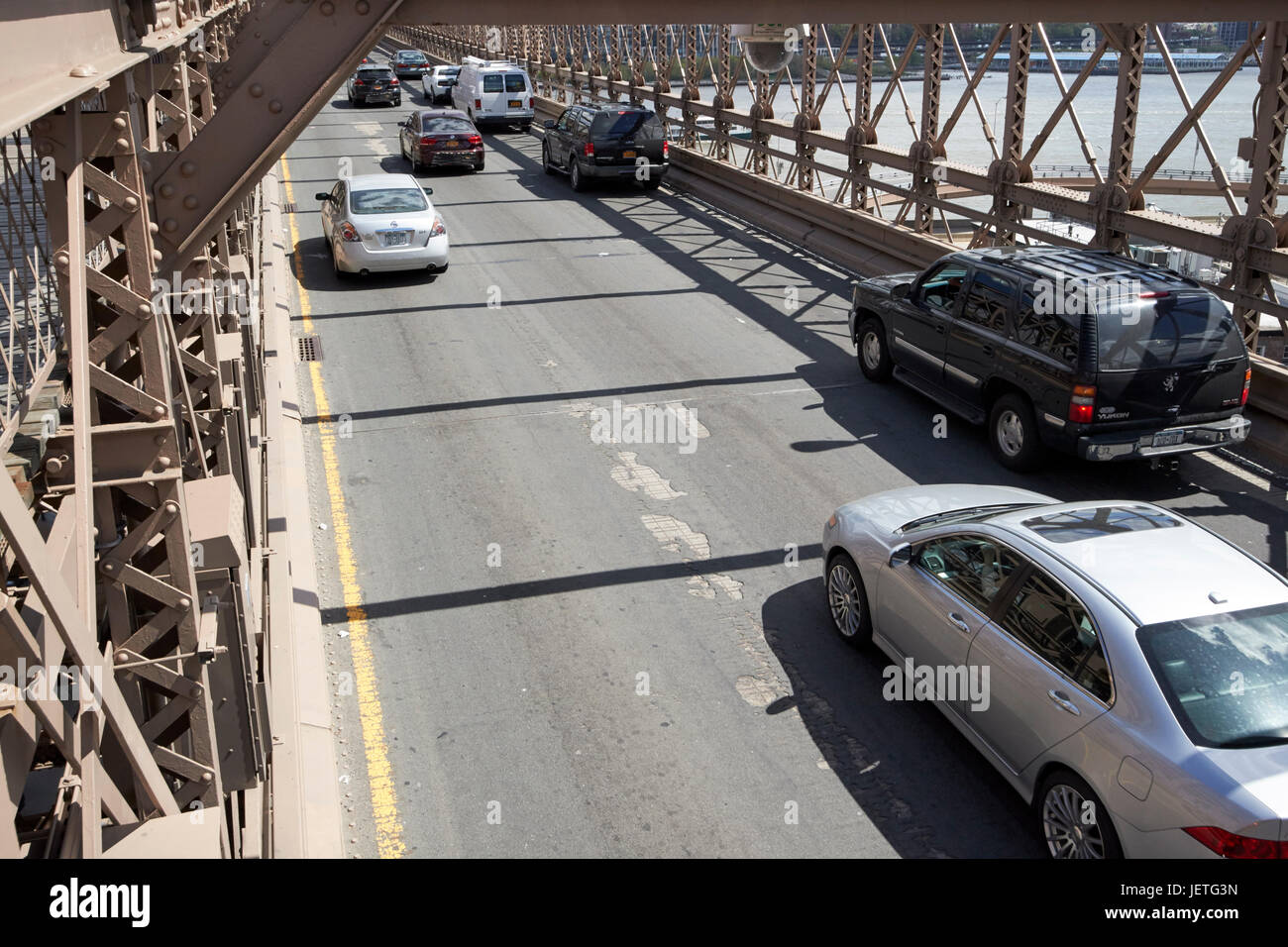 traffic vehicles driving over the worn tarmac on brooklyn bridge New York City USA Stock Photo