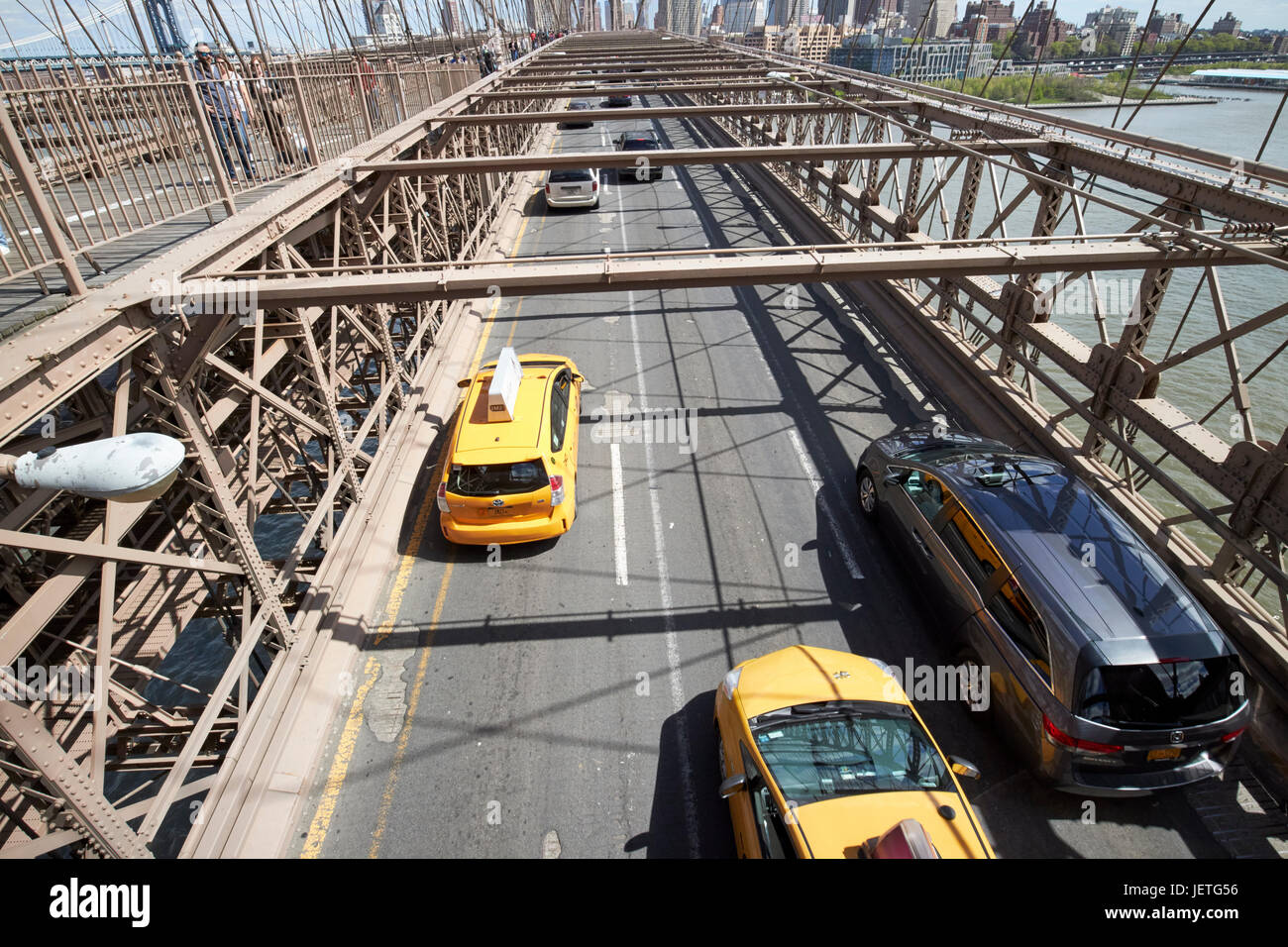yellow cabs traffic vehicles driving over the worn tarmac on brooklyn bridge New York City USA Stock Photo