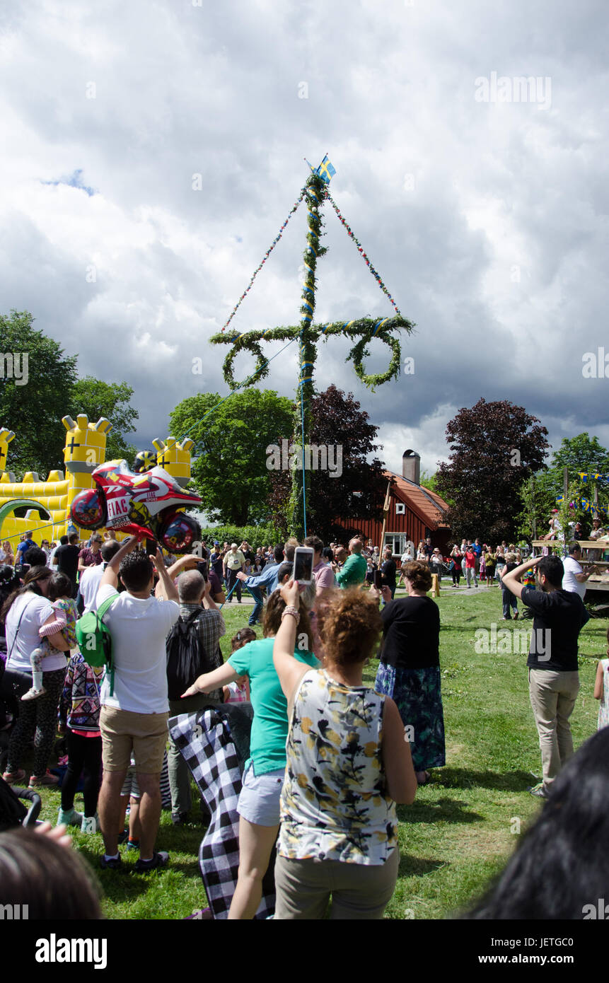 Stockholm, Sweden - June 23 2017. People celebrating the swedish holiday midsummer by raising the maypole covered in flowers and leaves in Akalla, a s Stock Photo