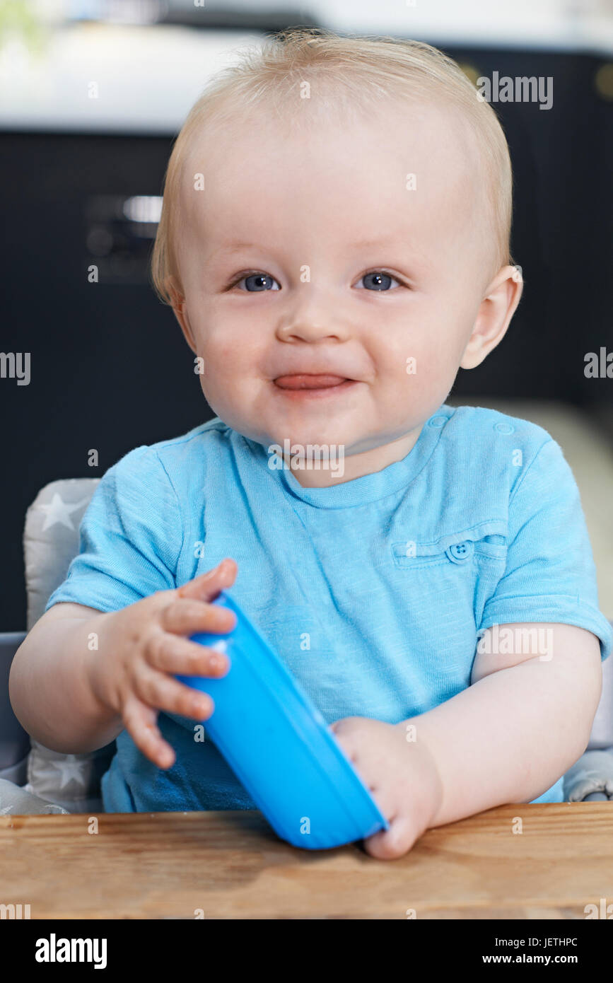 Happy Toddler With Empty Bowl Sitting At Table Stock Photo