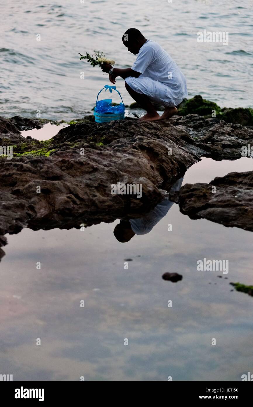 A Cadombleworshipper throws flowers in the sea during the celebration of Yemanya, the goddess of