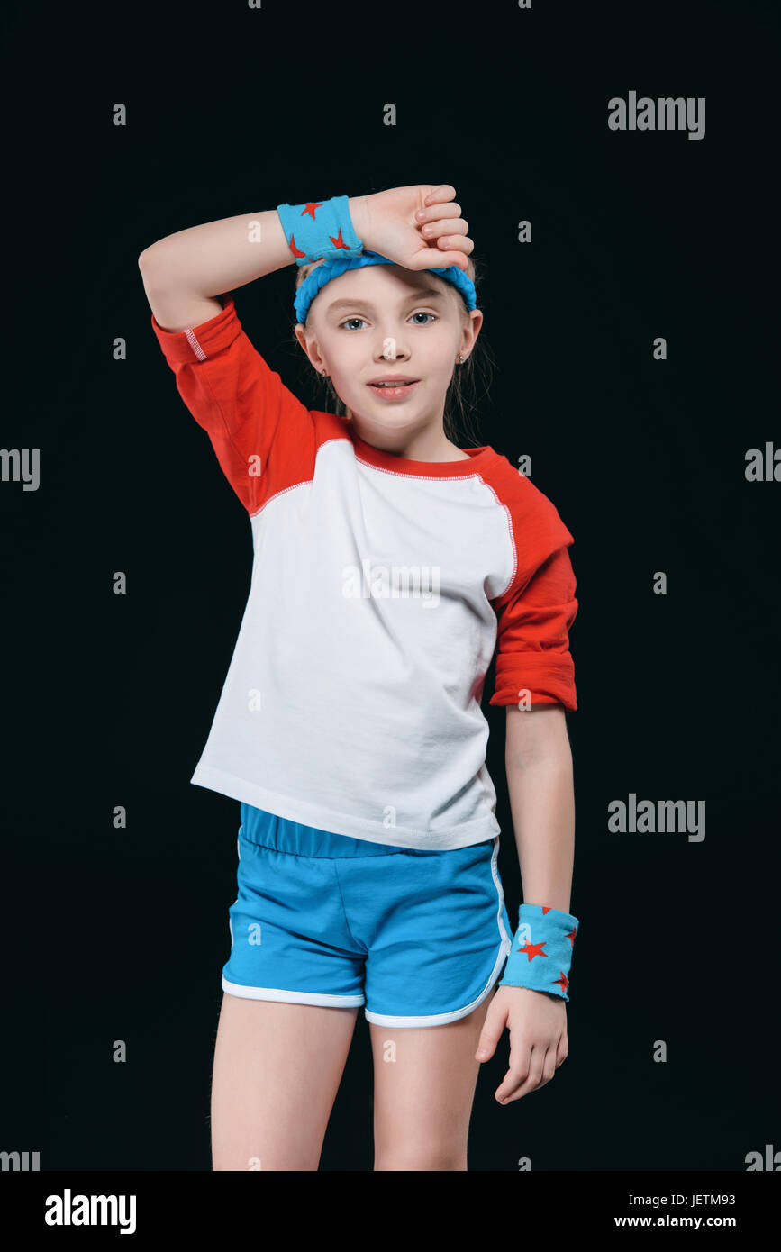 Tired little girl in sportswear wiping sweat from forehead, activities for children concept Stock Photo