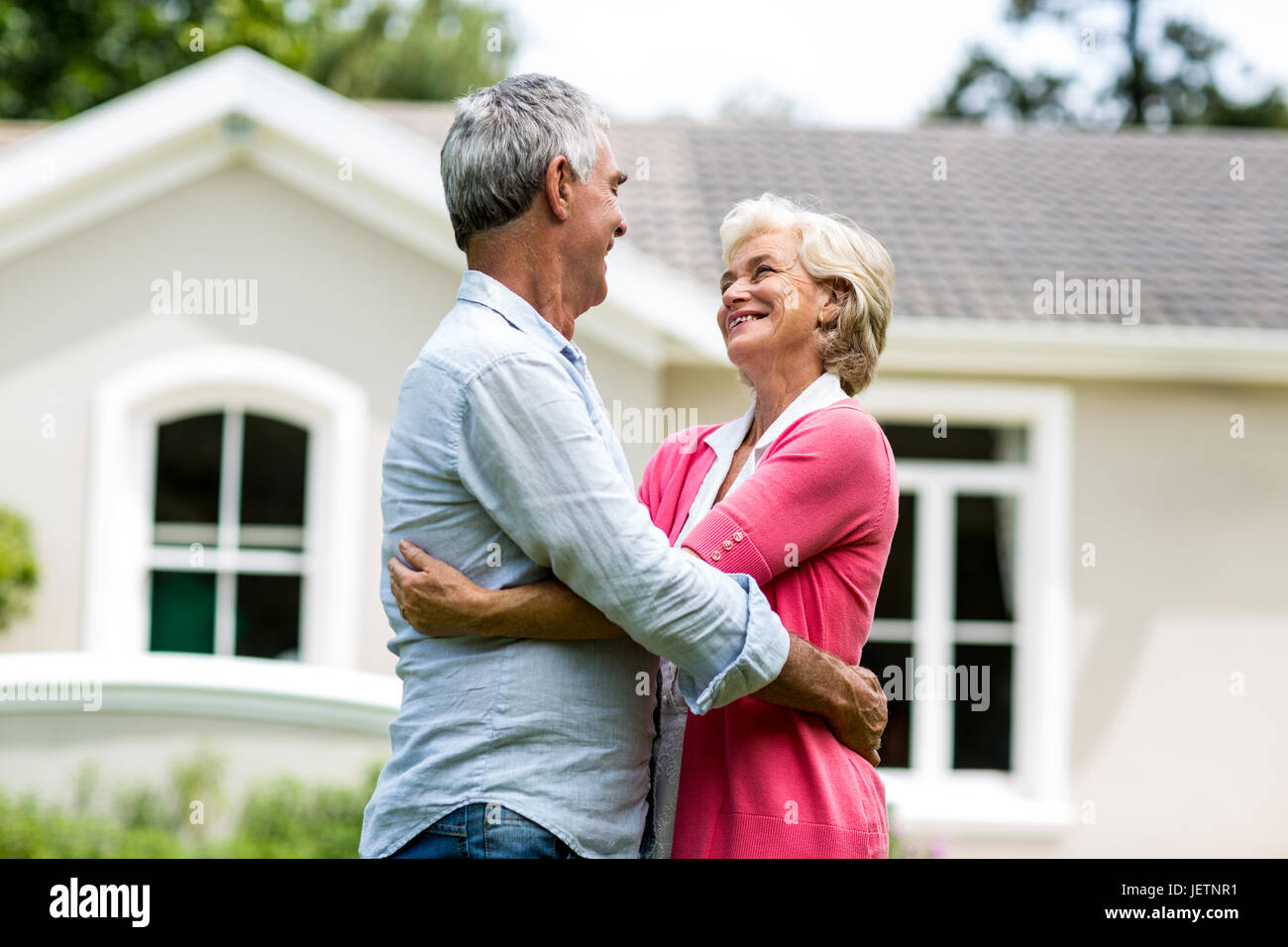 Smiling senior couple against house at yard Stock Photo - Alamy