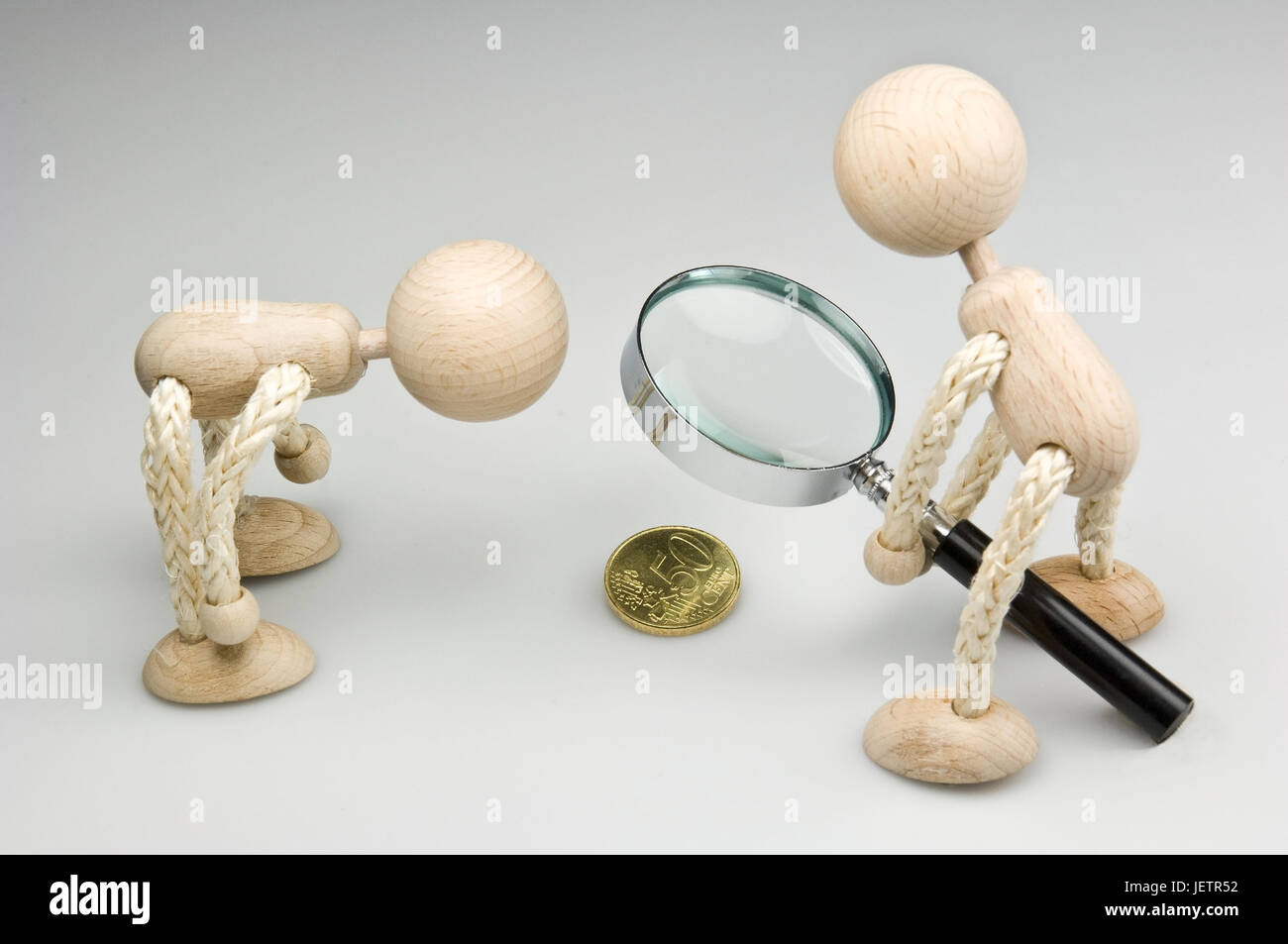 Two wooden figures with magnifying glass and 50 euro cent coin, Zwei Holzfiguren mit Lupe und 50-Eurocent-Muenze Stock Photo