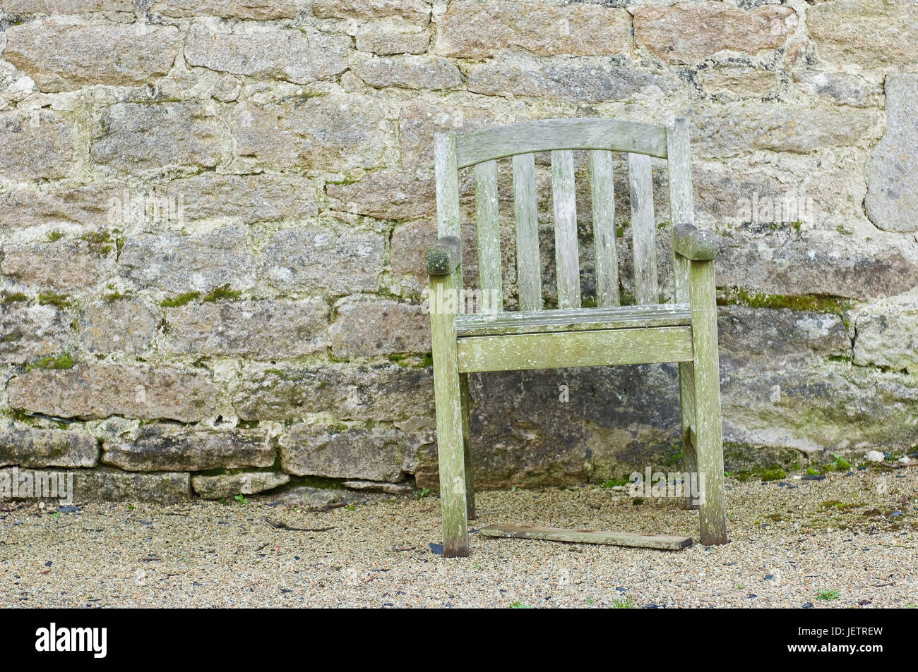 Rotting chair before a natural stone wall, Verrottender Stuhl vor einer Natursteinmauer Stock Photo