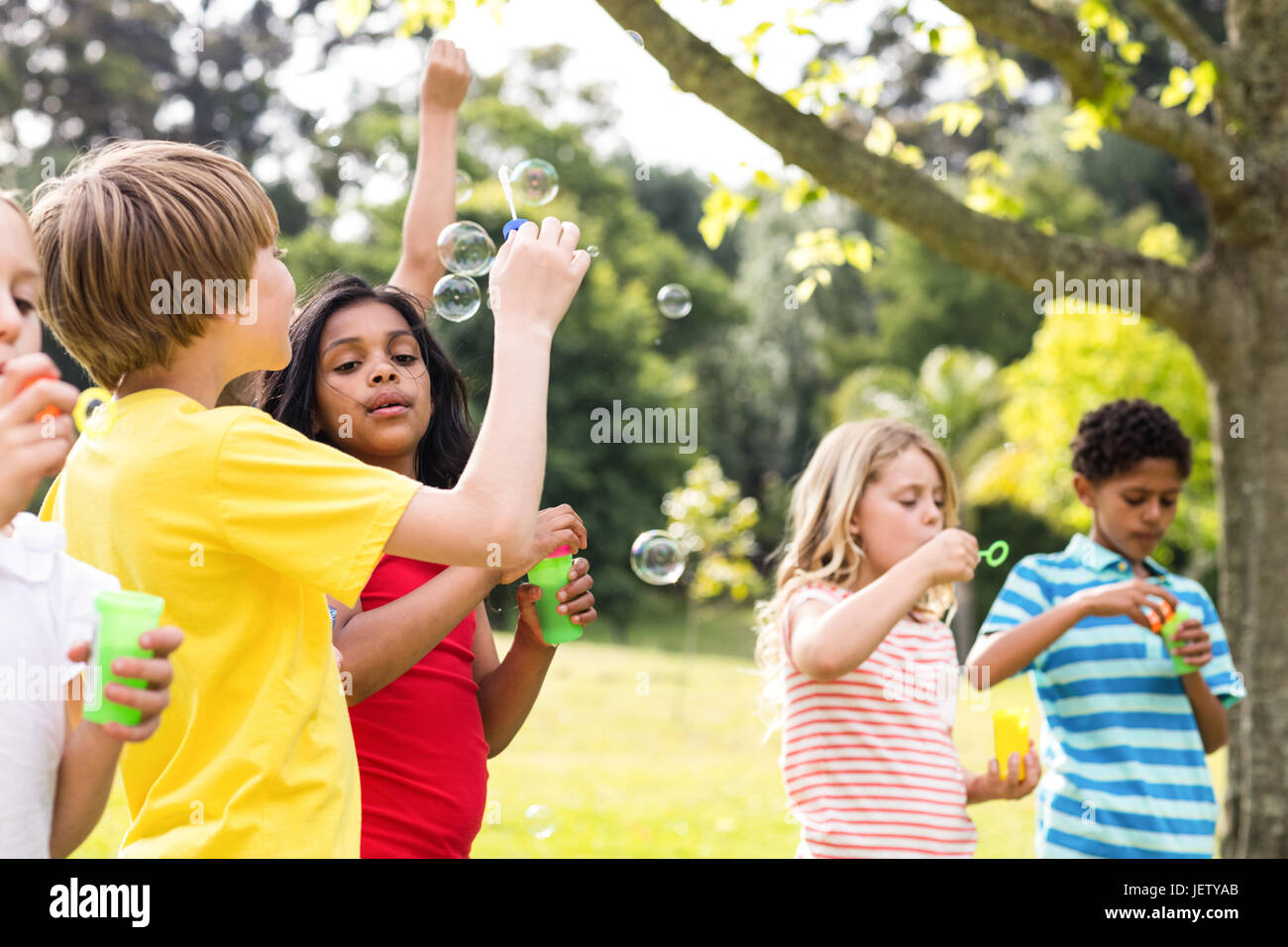 Children blowing bubbles wand in the park Stock Photo - Alamy