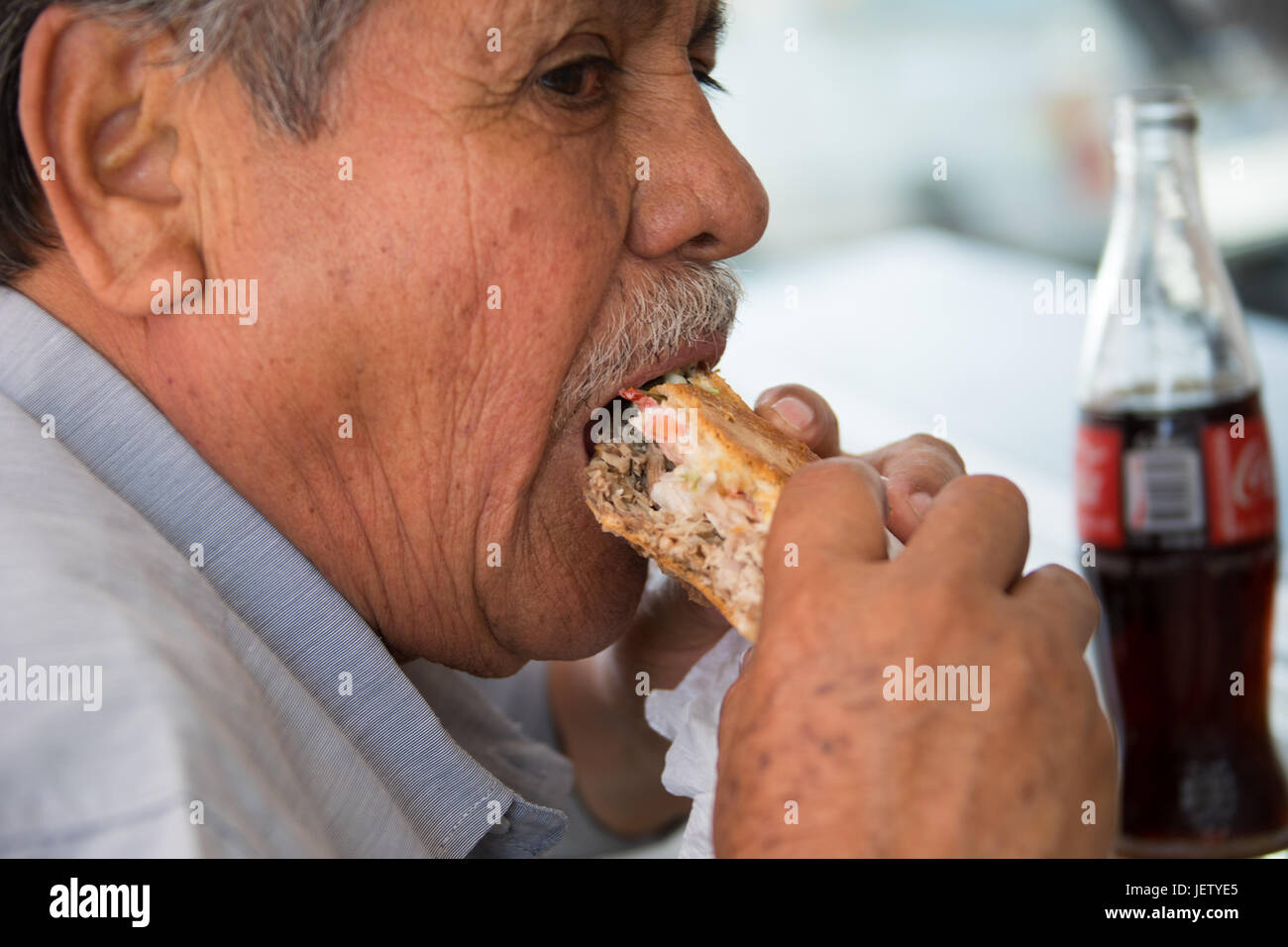 Local man eating a torta at a roadside restaurant in Oaxaca, Mexico Stock Photo