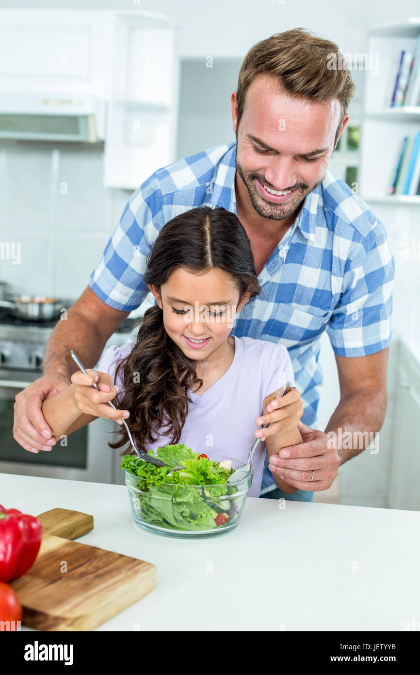 Father assisting daughter in preparing salad Stock Photo