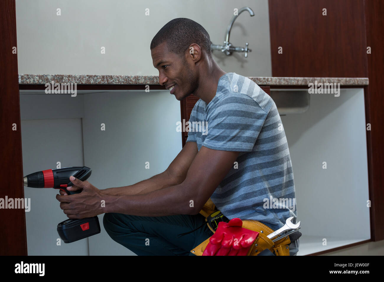 Manual worker drilling a hole in kitchen Stock Photo