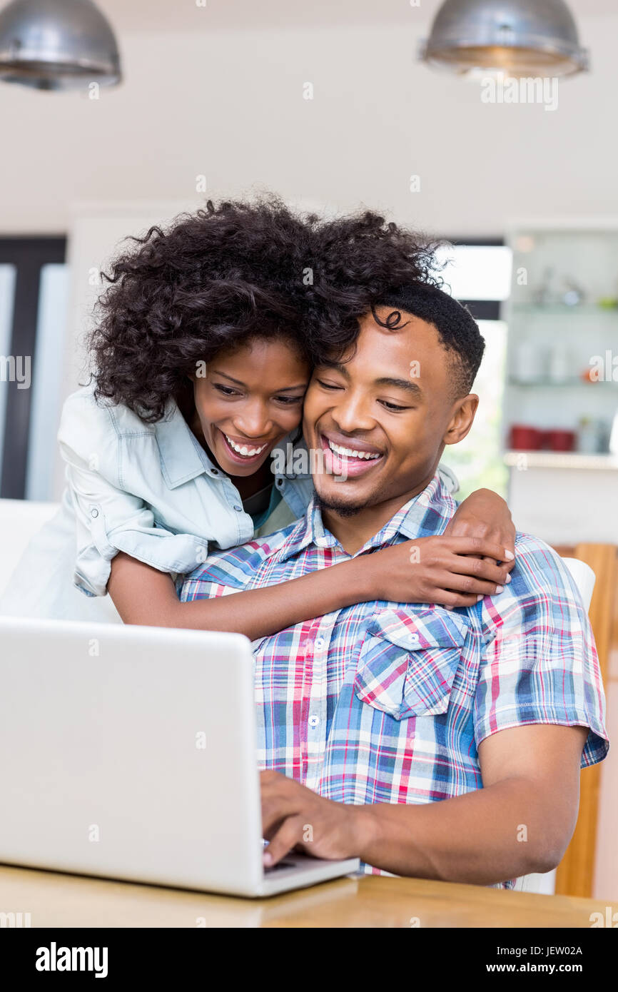 Happy young couple using laptop in kitchen Stock Photo - Alamy