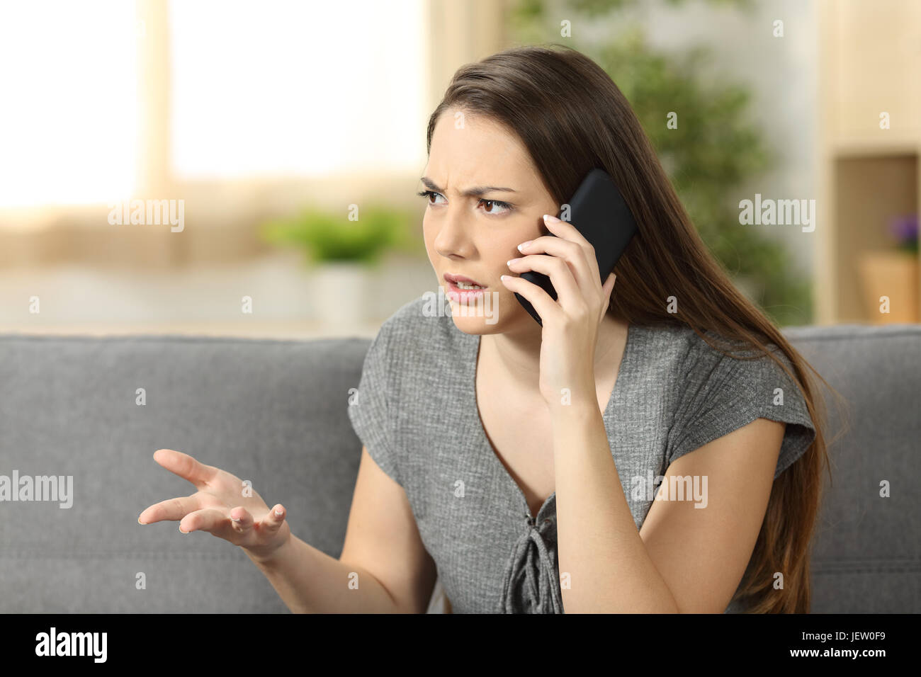 Angry woman arguing during a phone call sitting on a couch in the Stock Photo - Alamy